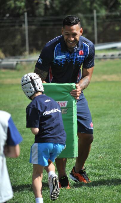 FOSTERING TALENT: Israel Folau readies himself for a big hit at Monday's clinic, he was among a host of Waratahs at Endeavour Oval. Photo: JUDE KEOGH