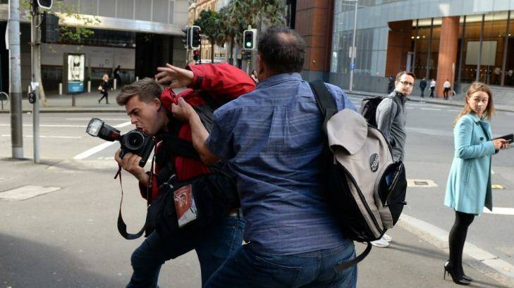Waiting in the wings: Bruce Wilson attacks a photographer outside the hearing.