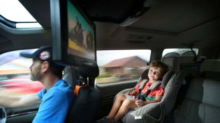 One in five parents turns to drugs: Orlando Moodley, 3, enjoys watching <i>Ice Age</i> on a DVD player while his dad Paul concentrates on driving. Photo: James Alcock