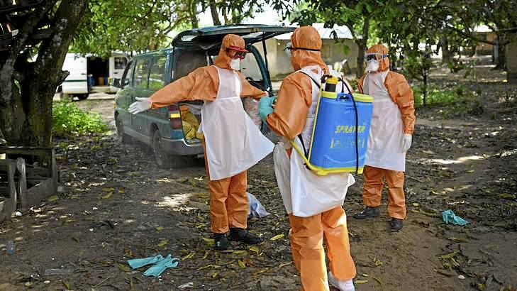 Members of a burial team spray themselves with chlorine after removing the body of a suspected Ebola victim from a home in Waterloo, Sierra Leone. Photo: New York Times