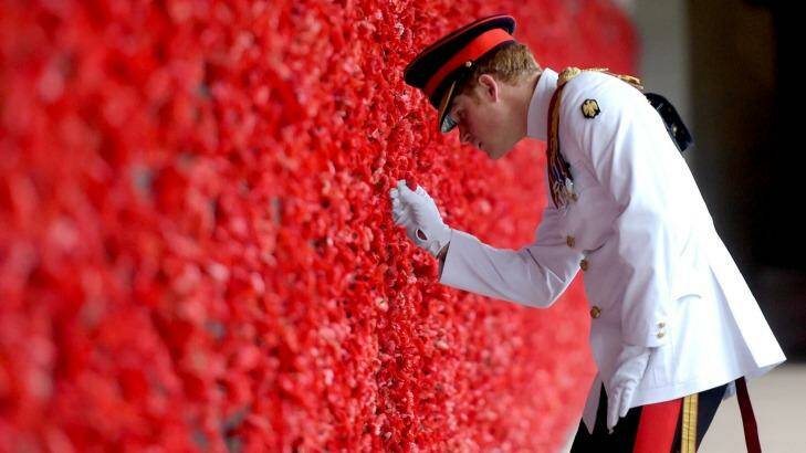 Prince Harry places a poppy at the Roll of Honour during a visit to the Australian War Memorial on April 6, 2015 in Canberra.