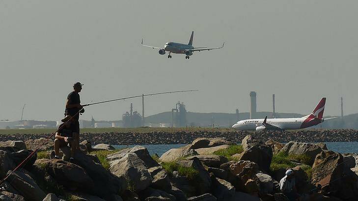 Two men fishing at Botany Bay as planes come into land and prepare to take off at Sydney Airport. Photo: Kate Geraghty