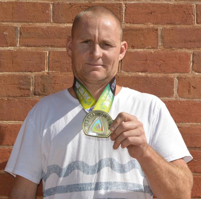 John Wheele proudly displays his winner’s medal from the Penrith paratriathlon. 0416Wheele