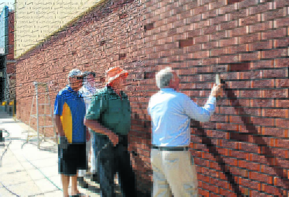 Rotarians, Peter Woods, John Short, Peter Thompson and Cliff Cowell work hard to remove graffiti from a wall in Court Street.