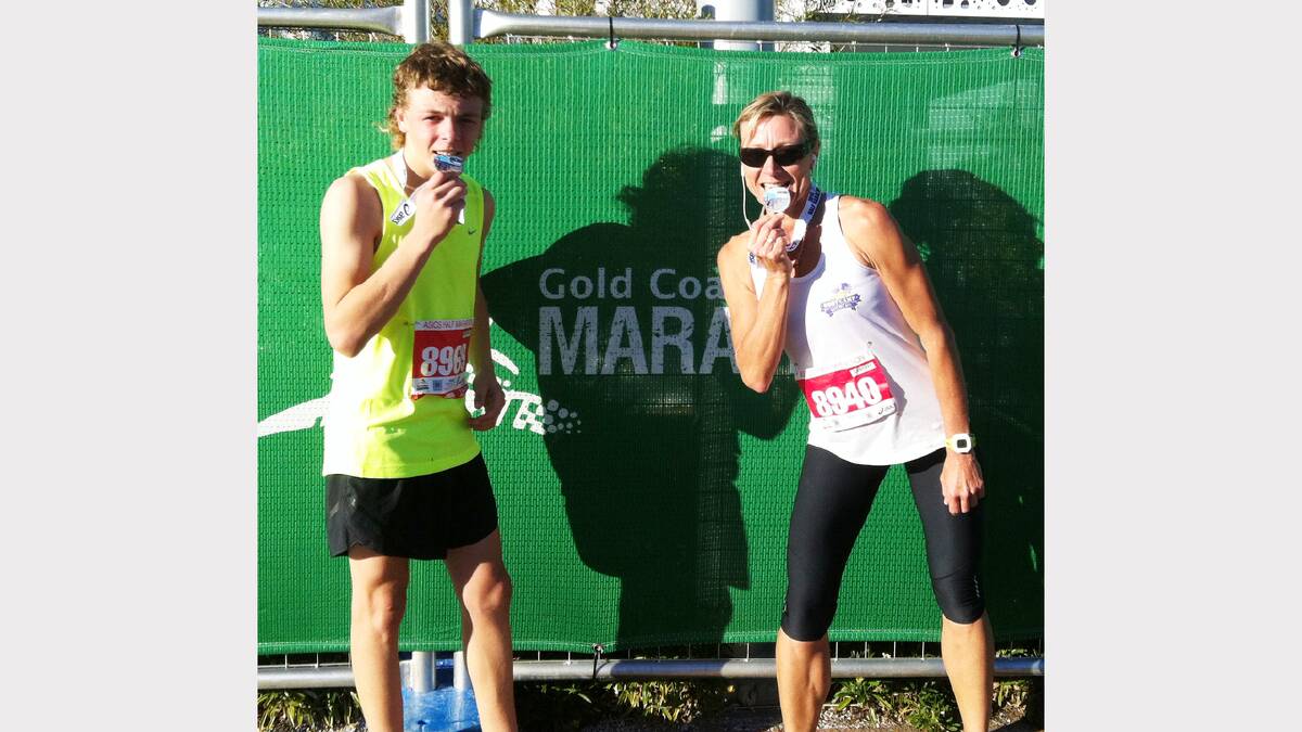 Parkes runners Michael McGrath and Sonia Davies take a bite from their Gold Coast Marathon medals. sub