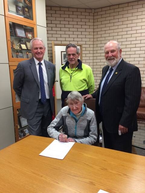 President of the Parkes and District Historical Society, Yvonne Hutton (front) signs the lease with Parkes Shire Council's General Manager Kent Boyd, Bruce Hall, and Mayor Cr Ken Keith OAM.