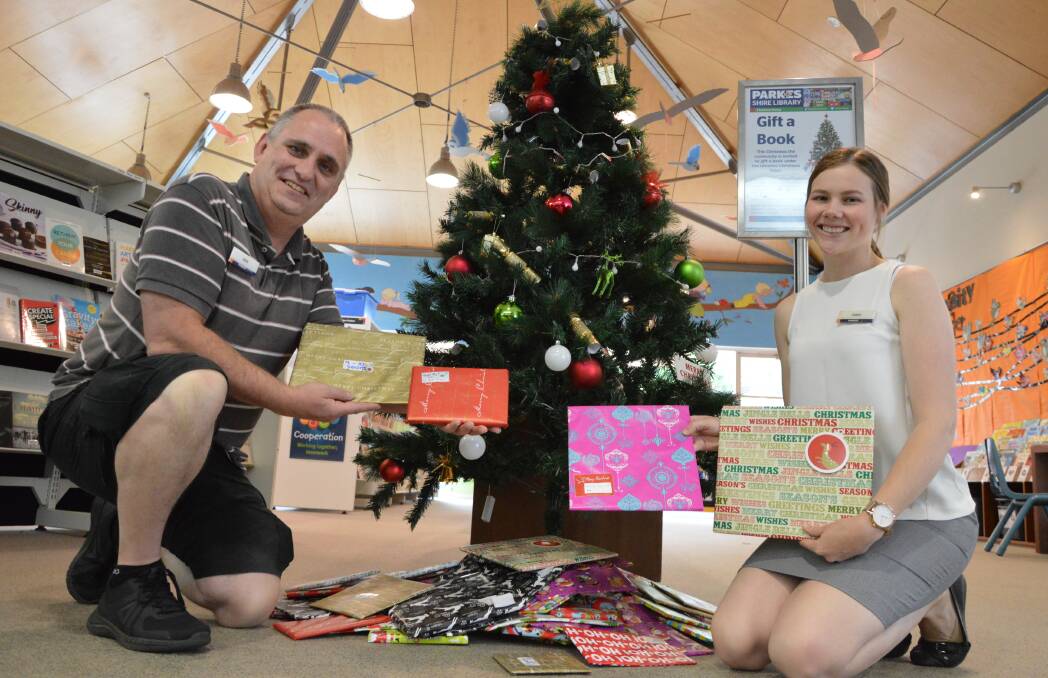 BOOK-LOADS: Parkes Shire Library staff Dan Fredericks and Claire Cassell are excited to see so many books already under their Christmas tree. Photo: Christine Little
