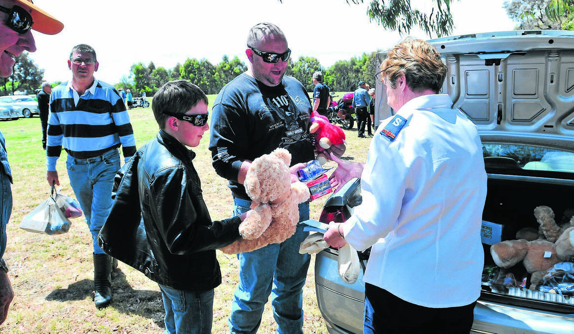 ORANGE: Toy Run contributors Joel Woods and his dad Tim hand over their presents to Dianne Cooper of the Salvation Army so less fortunate children will have presents on Christmas Day. Photo: JUDE KEOGH