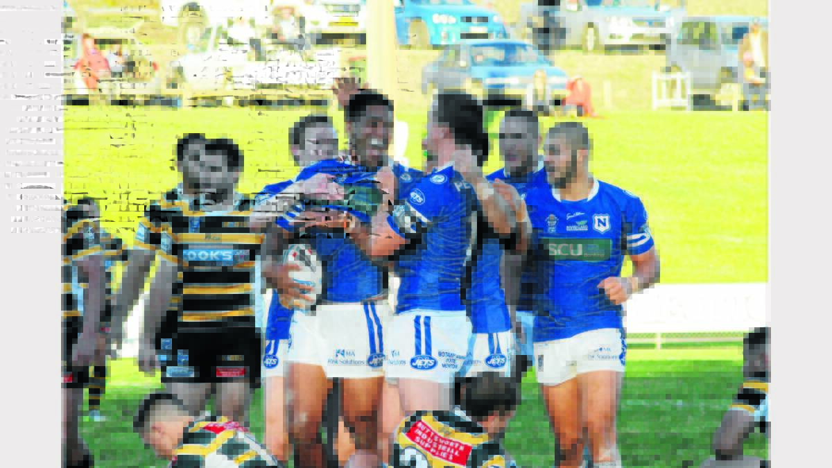 Lama Tasi celebrates with team mates after scoring a late try for the Newtown Jets at Pioneer Oval yesterday.