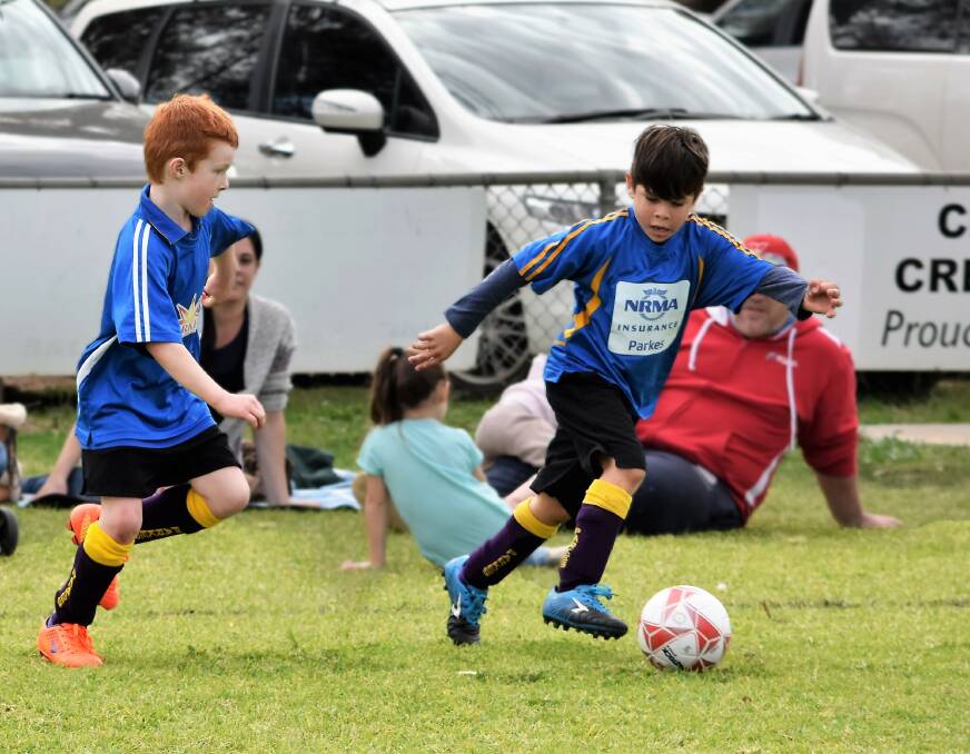 Caption - THE BIG CHASE: Parkes Services Club player Harry Yelland was hot on the heels of NRMA's Kalvin Dargan during a junior soccer match at Harrison Park last month. Photo: Jenny Kingham