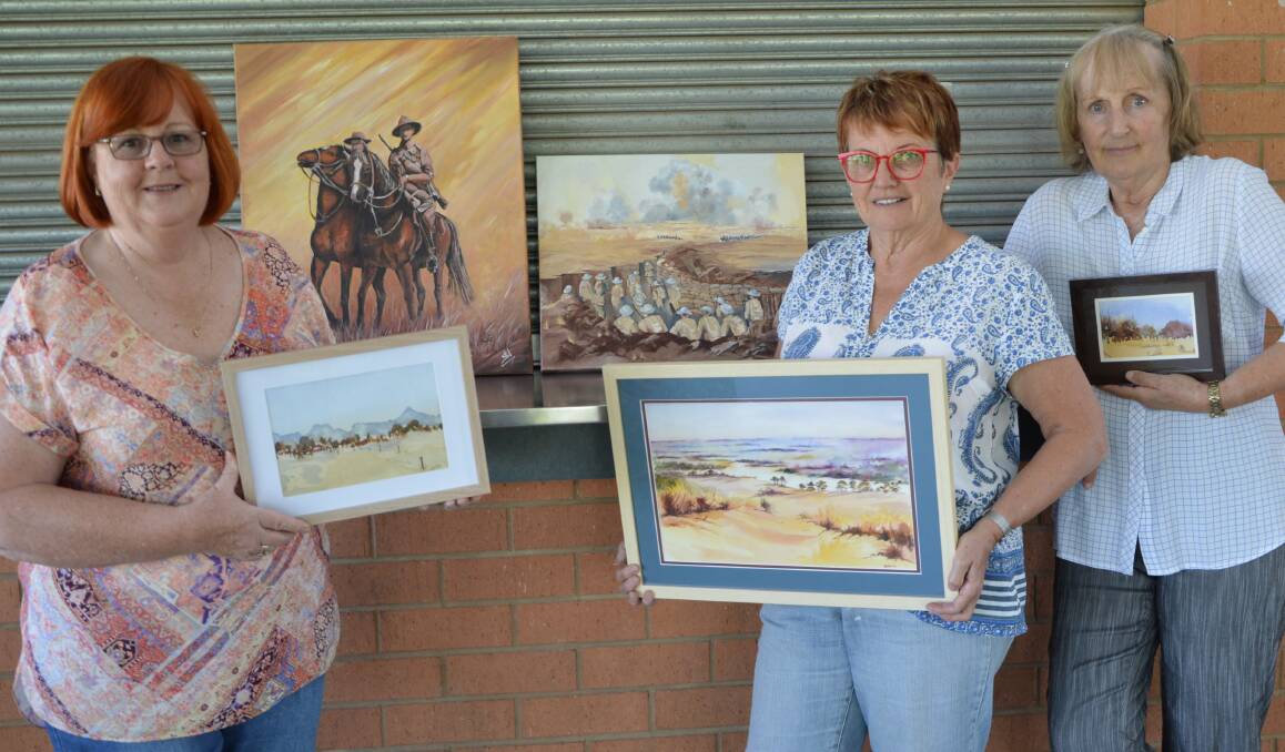 ANZAC THEME: Annette Witherow, Di Hutchins and Sue Woods with some of the Anzac themed artworks to be featured in the 2019 Parkes Painting Group exhibition. Photo: Barbara Reeves.  
