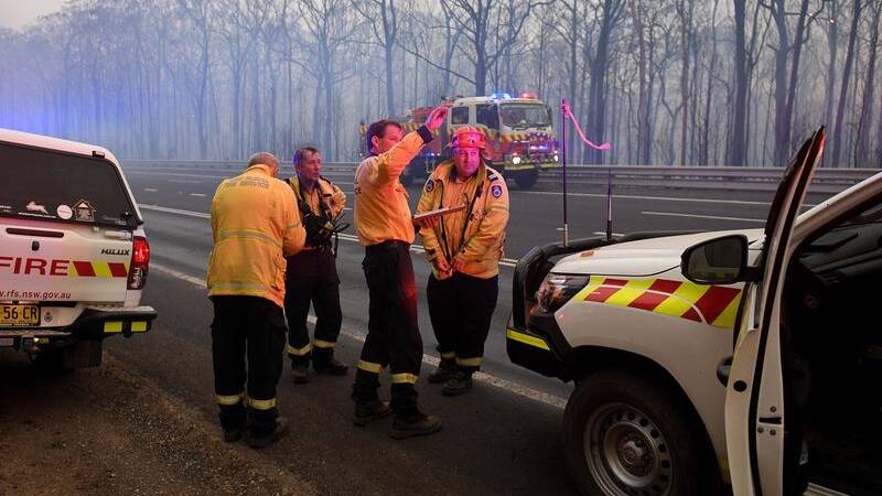 ACTION: Firefighters plan their next move amid the devastation of two out of control bush fires on the Blue Mountains.