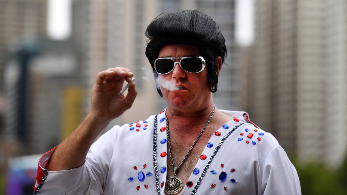 Elvis impersonator Gary Churchill smokes a cigarette before boarding the Elvis Express at Central Station. Photo: AAP