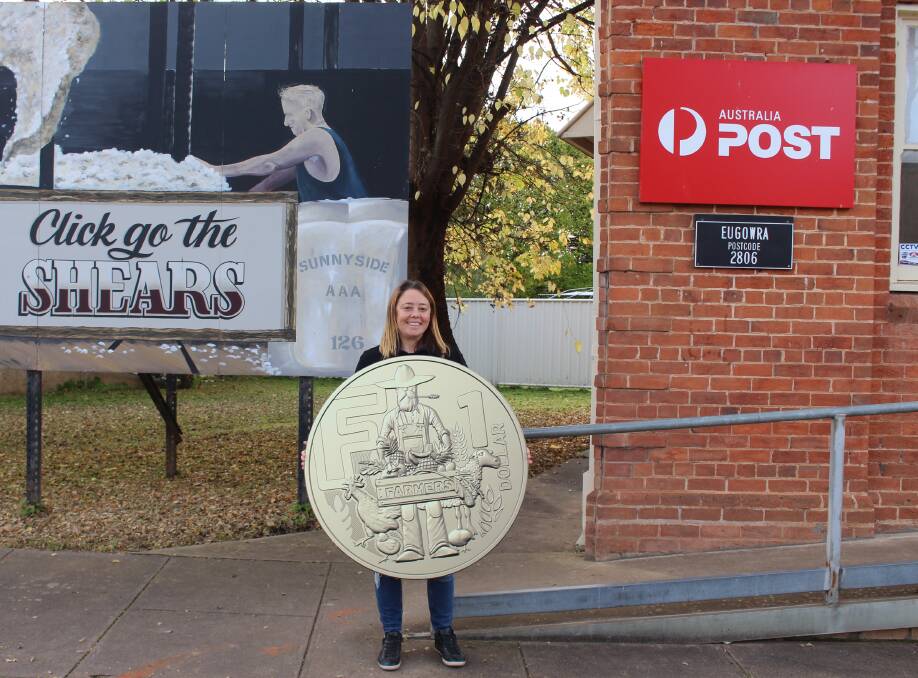 Kathy Fren shows off an enlarged version of the unique coin which features F for Farmers.