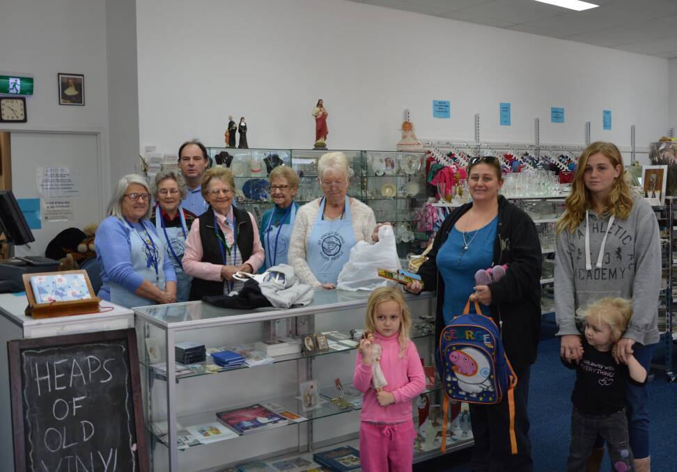 Many hands make light work: Vinnie volunteers Raiechll Giles, Pat Byrne, Brian Dow, Trish Davies, Elvie Collins and Barbara Scott,  serving customers, Kylie Powell, and her three daughters Kira, Paige and Bianca. Photo: Supplied.