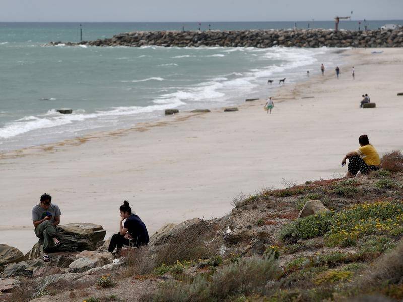 People continue to swim near a breakwater at Glenelg beach despite warning signs.