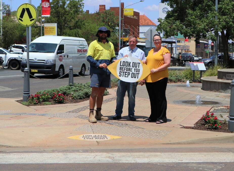 STICK TO IT: Parkes Shire Council's concrete works team leader Ricky Newham, Cr George Pratt and Road Safety and Injury Prevention Officer Melanie Suitor installing pedestrian safety stickers in Clarinda Street and across the Parkes Shire. Photo: Submitted