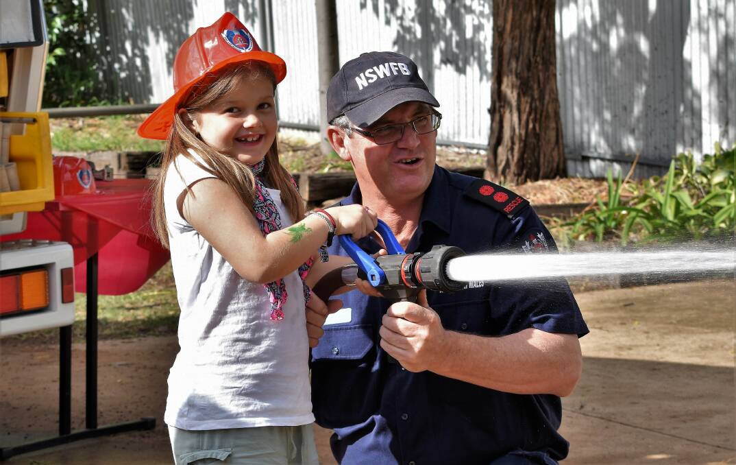 Phoebe Hale enjoyed using the fire hose with Captain Craig Gibson during the Parkes Fire Station open day last year. Photo: Jenny Kingham

