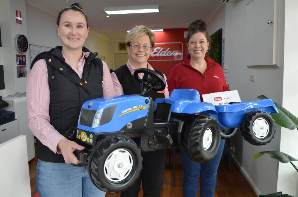 UP FOR GRABS: Tiffany Doughty, Belinda Harris and Janna Flanagan from Elders Real Estate in Parkes with the toy tractor that's waiting to be won. Photo: CHRISTINE LITTLE