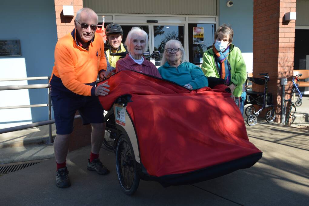 Volunteer cyclists Peter Guppy and Geoff Wyatt with BaptistCare Niola Aged Care residents Dawn Caterson and Jean Murray, and onlooker Barbara Guppy, during one of their weekly visits. Photo by Christine Little