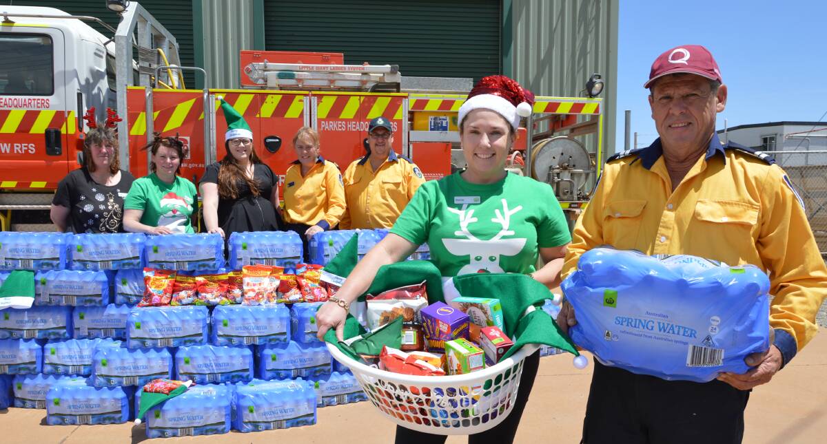 VALUABLE RESOURCE: Parkes Woolworths store manager Kerrie Kennedy and Parkes Headquarters Rural Fire Brigade senior deputy captain Steve Chester (both right), with staff and firefighters and the donation of 1440 bottles of water and packets of lollies and snacks. Photo: Christine Little