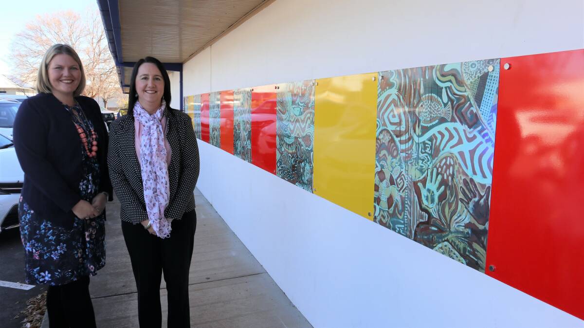 NEW HOME: Parkes Shire Council's Destination Development Manager Kelly Hendry and Wilcannia Forbes Central Council Executive Officer of the St Vincent de Paul Society Kelly Morgan are delighted to see the artwork repurposed ahead of NAIDOC Week 2019. Photo: Submitted
