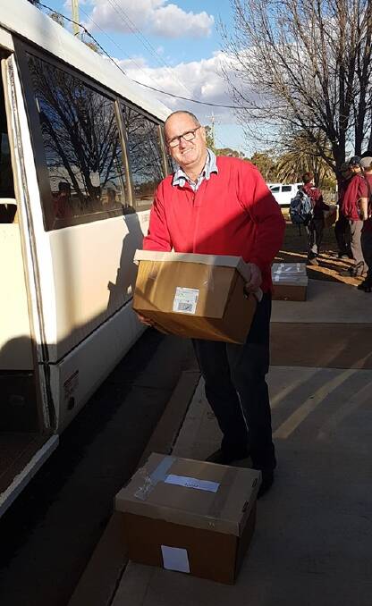 DROUGHT RELIEF: Trundle Central School principal John Southon doing what he does best. This is him in July 2019, packing the 500th hamper of food and toiletries for a school family during the drought. Photo: Trundle Central School Facebook page