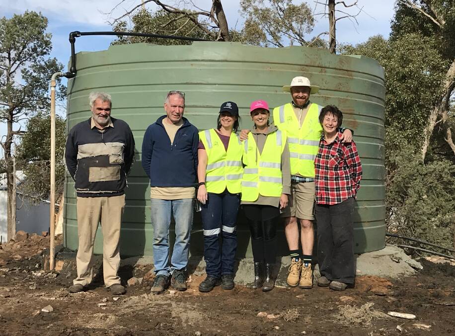 RURAL AID FARM ARMY: Rural Aid volunteers tore down an old leaking concrete water tank on Tony and Rhonda Milgate's farm in Trundle and replaced it with a new one. Photo: Grant Miskimmin