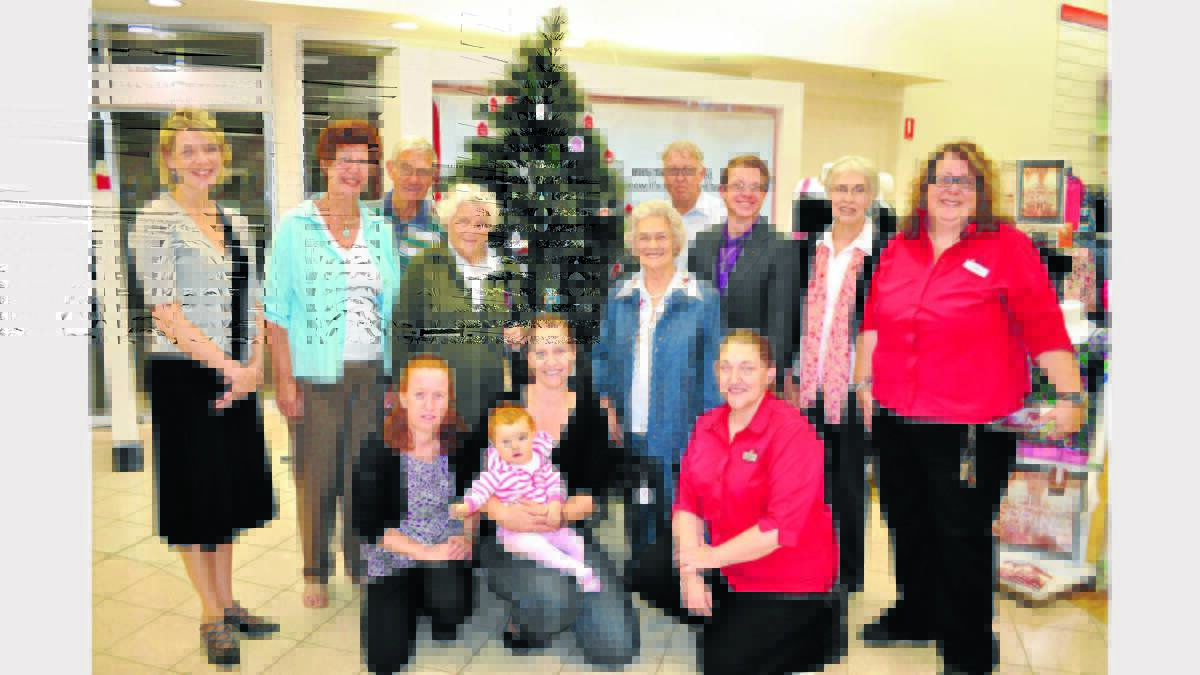 Representatives of various agencies along with Target Country staff assembled for the launch of this year’s `Operation Santa’ Christmas appeal. Pictured (back-row, left to right) Janice Evanson (Anglicare), Joan and Ian Mill (Uniting Church), Margaret Morrison (Uniting Church), Jim Rogers (St Vincent de Paul), Mary Stuart (Uniting Care), James Whalan (Uniting Care), Evelyn Shallvey (Uniting Care) and Sue Brown (Target Sales Manager); front: Tracey Ganzerla (Target sales), Kylie Everson nursing 9-month-old Layne and Katrina Bonfield (Target acting store manager).  Photo: Bill Jayet 1112Targettree  